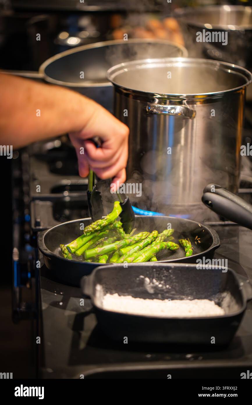 Aghi di asparagi verdi fumanti in una padella di ghisa su un piano a gas, preparati per una cena di lusso in una cucina di casa di campagna, Scozia, Regno Unito Foto Stock