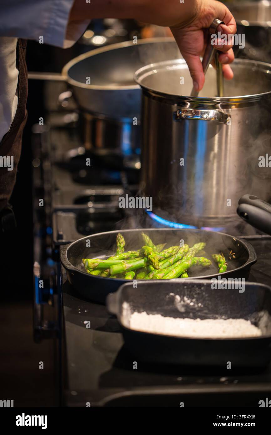 Aghi di asparagi verdi fumanti in una padella di ghisa su un piano a gas, preparati per una cena di lusso in una cucina di casa di campagna, Scozia, Regno Unito Foto Stock