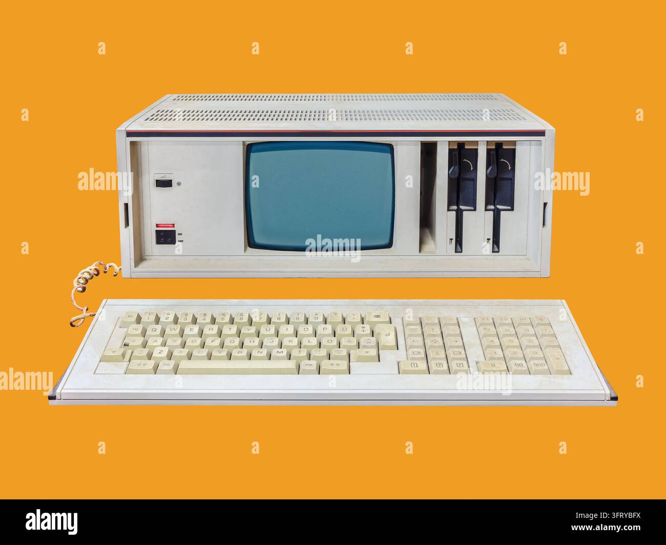 Computer desktop portatile vintage degli anni ottanta con display CRT e unità floppy su sfondo arancione Foto Stock