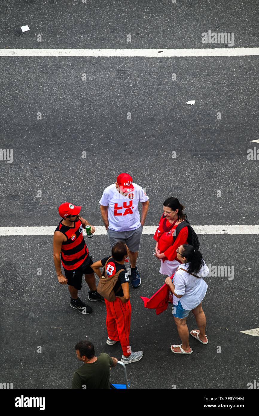 Rio de Janeiro, Brasile – 12 ottobre 2026: Veduta aerea di sostenitori che indossano abiti rossi e cappelli con il branding di Lula radunati su una strada. Foto Stock