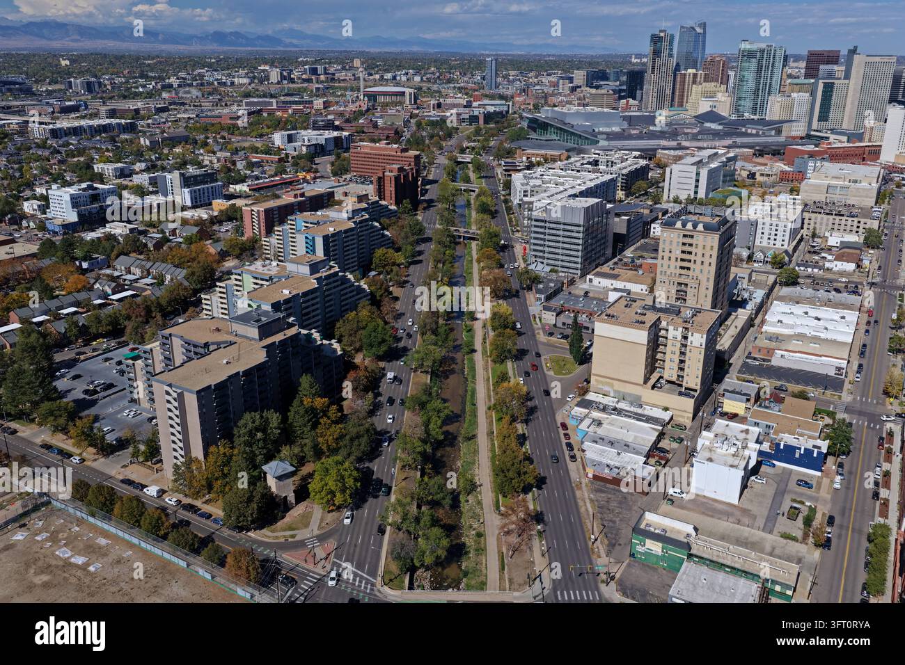 Vista aerea dello skyline di Denver, con grattacieli moderni, strade urbane e il sentiero di Cherry Creek fiancheggiato da alberi sotto un cielo blu limpido in Foto Stock