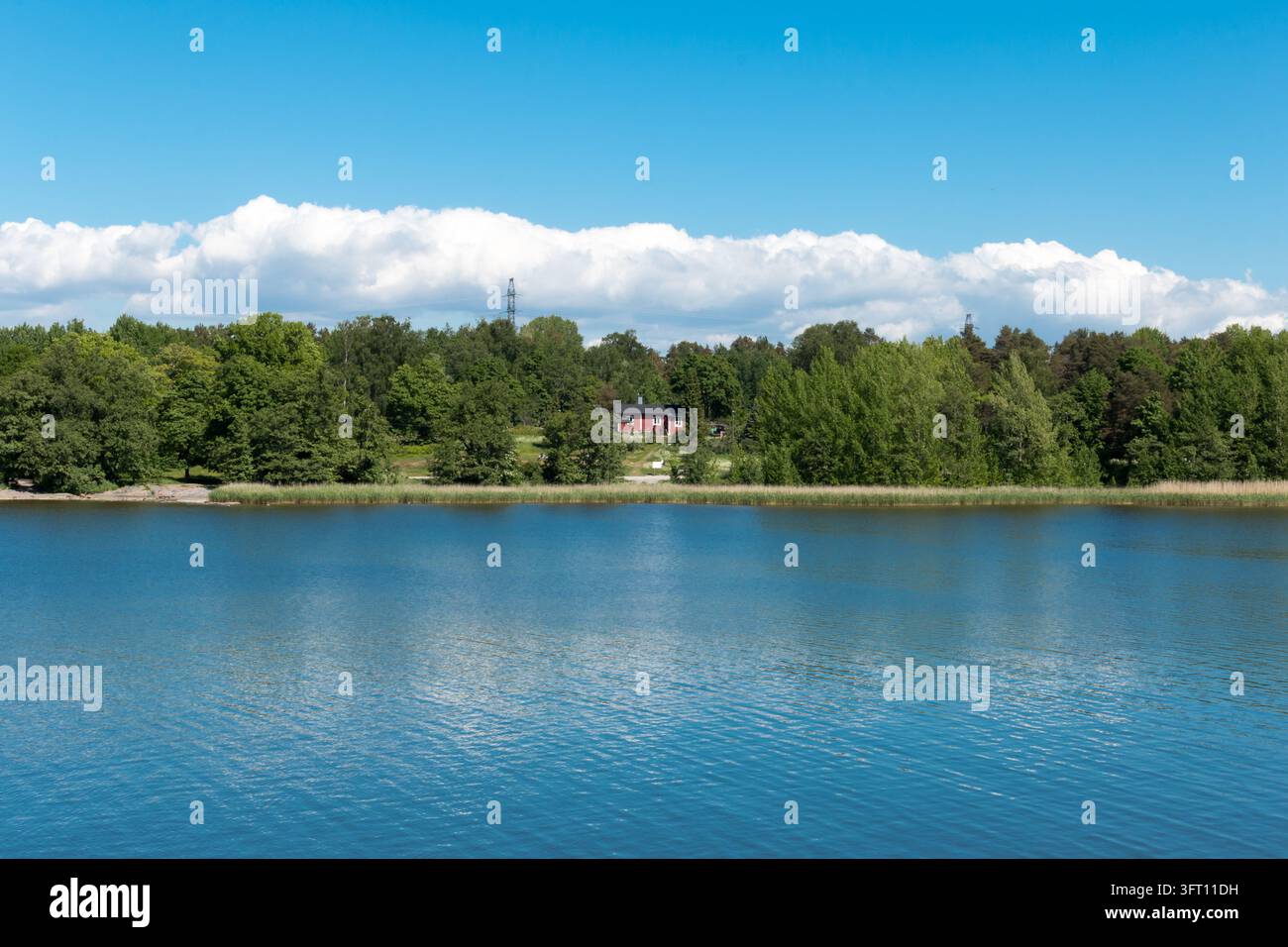 Una vista panoramica del quartiere marittimo di Kulosaari attraverso le acque calme dall'isola di Mustikkamaa a Helsinki, in Finlandia, in una luminosa e soleggiata giornata estiva. Foto Stock