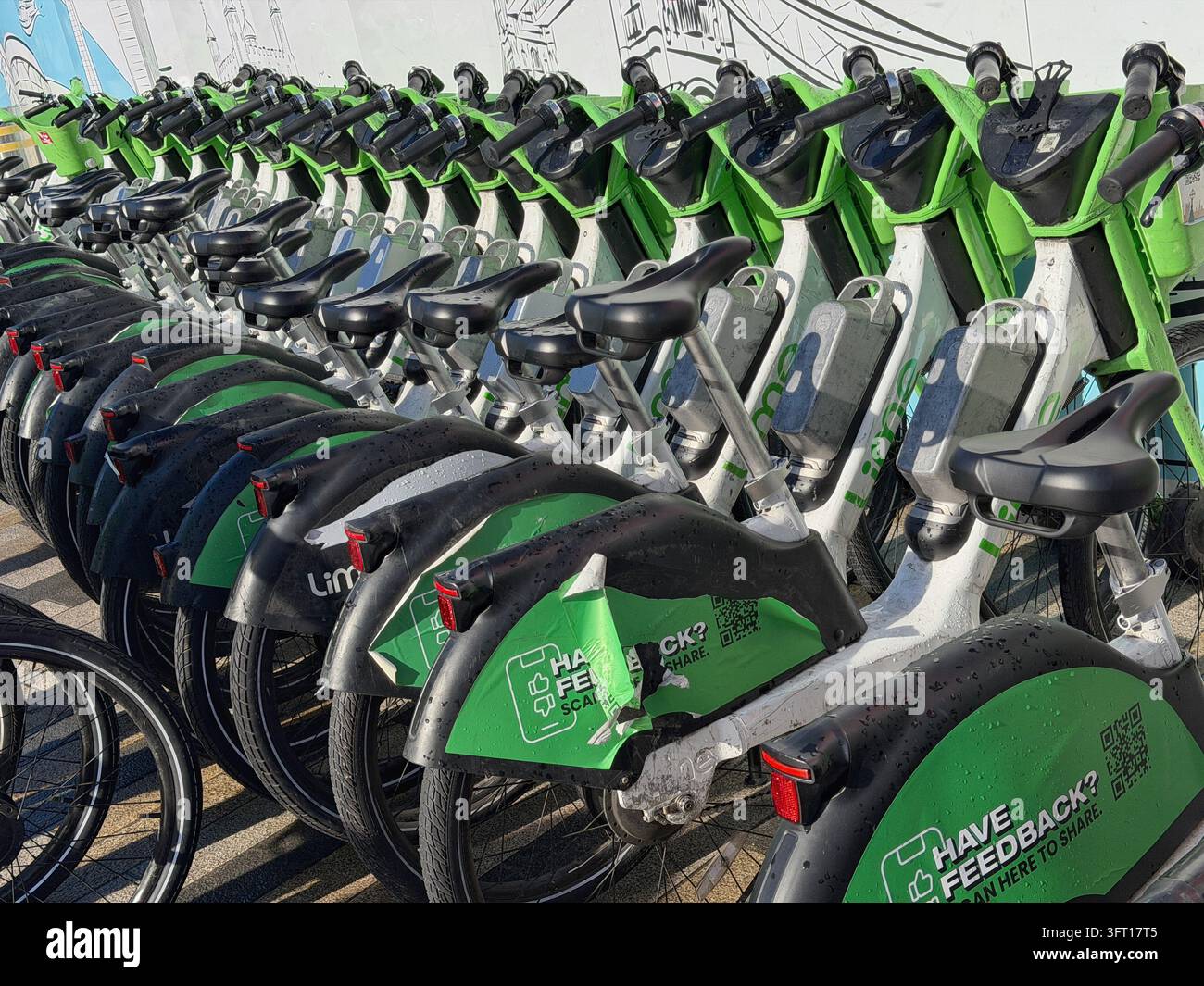 Biciclette Lime parcheggiate vicino alla Battersea Power Station nel centro di Londra. Le biciclette sono dotate di un sistema di assistenza al pedale che si attiva mentre si pedala. - Immagine stock catturata con smartphone