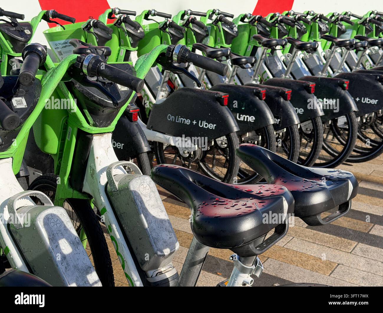 Biciclette Lime parcheggiate vicino alla Battersea Power Station nel centro di Londra. Le biciclette sono dotate di un sistema di assistenza al pedale che si attiva mentre si pedala. - Immagine stock catturata con smartphone