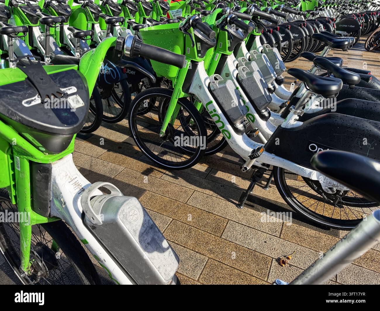 Biciclette Lime parcheggiate vicino alla Battersea Power Station nel centro di Londra. Le biciclette sono dotate di un sistema di assistenza al pedale che si attiva mentre si pedala. - Immagine stock catturata con smartphone