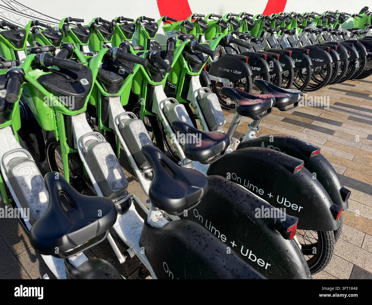 Biciclette Lime parcheggiate vicino alla Battersea Power Station nel centro di Londra. Le biciclette sono dotate di un sistema di assistenza al pedale che si attiva mentre si pedala. - Immagine stock catturata con smartphone