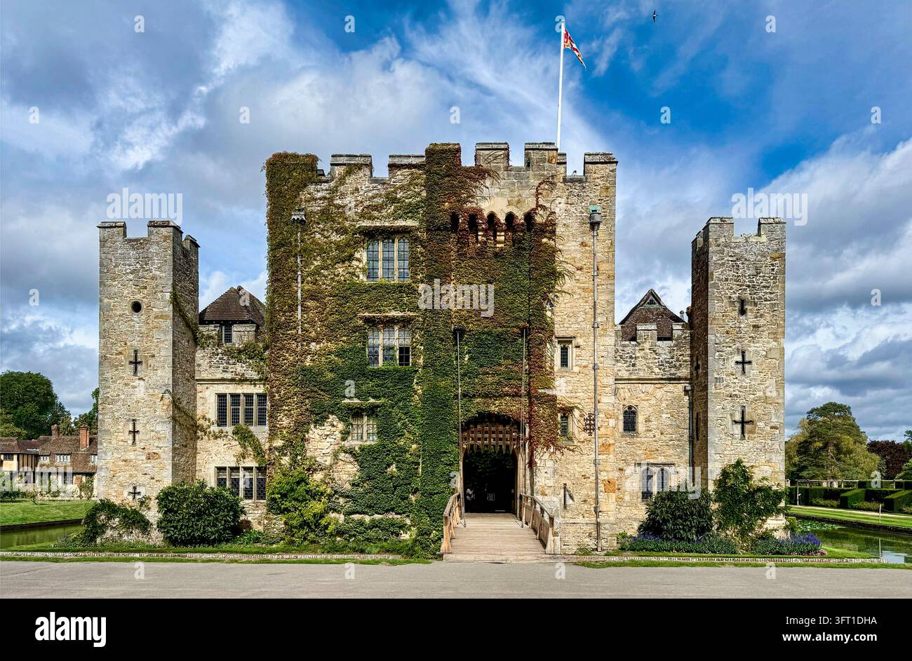 Hever Castle nel Kent, Inghilterra, castello medievale storico circondato da un fossato, con mura in pietra ricoperte di edera, torri e una bandiera Union Jack. Foto Stock