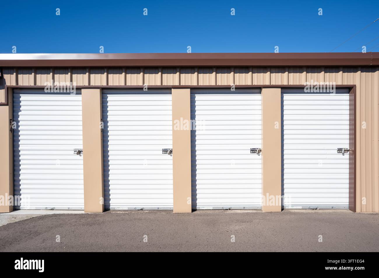 Vista di porte di unità di stoccaggio a rullo in metallo bianco con lucchetti e rivestimento marrone chiaro nel Colorado, Stati Uniti. Foto Stock