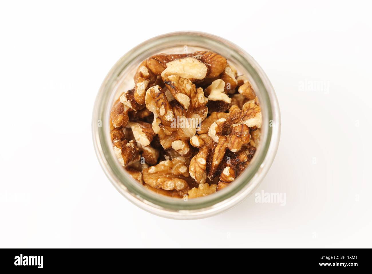 Mezze noci e pezzi di noce in barattolo di vetro su sfondo bianco. Composizione alimentare sana per noci naturali, ingredienti per dolci, grassi omega e nutrienti Foto Stock