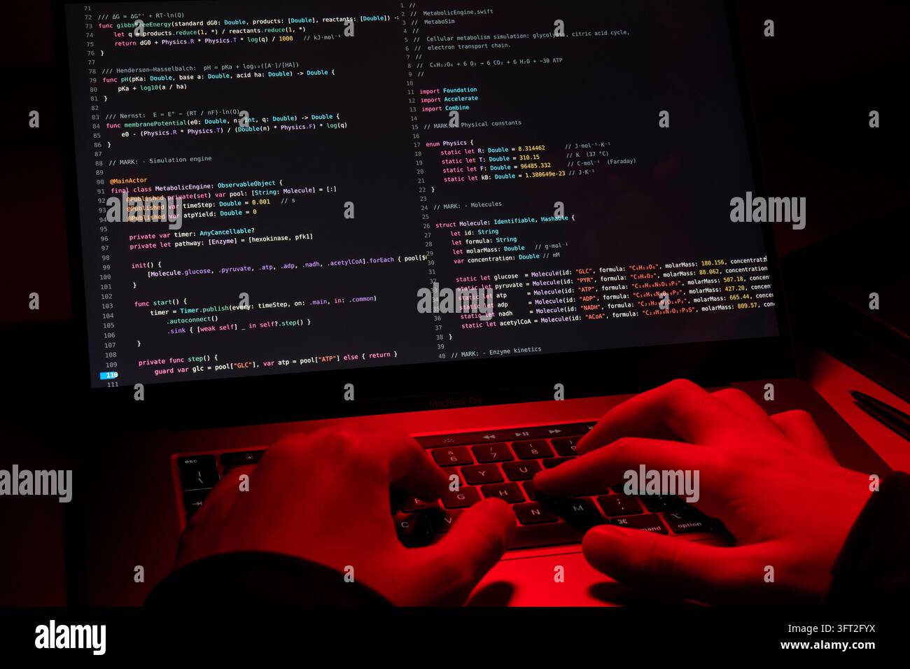 Hacker che digita codice di programmazione su un laptop sotto luce rossa Foto Stock