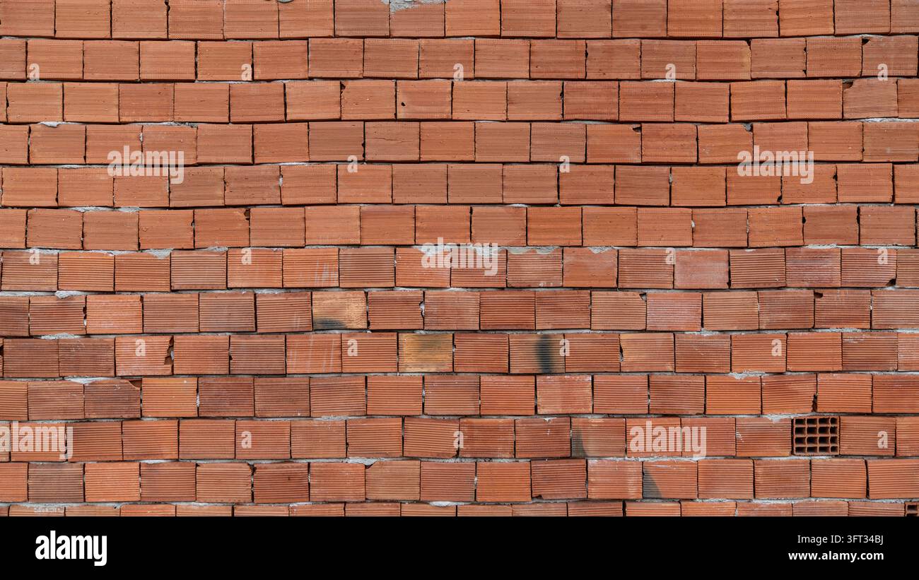 Muro di mattoni cavi rossi di una casa in costruzione, non intonacato con giunti di malta ruvidi, una texture di muro di mattoni a cornice intera Foto Stock