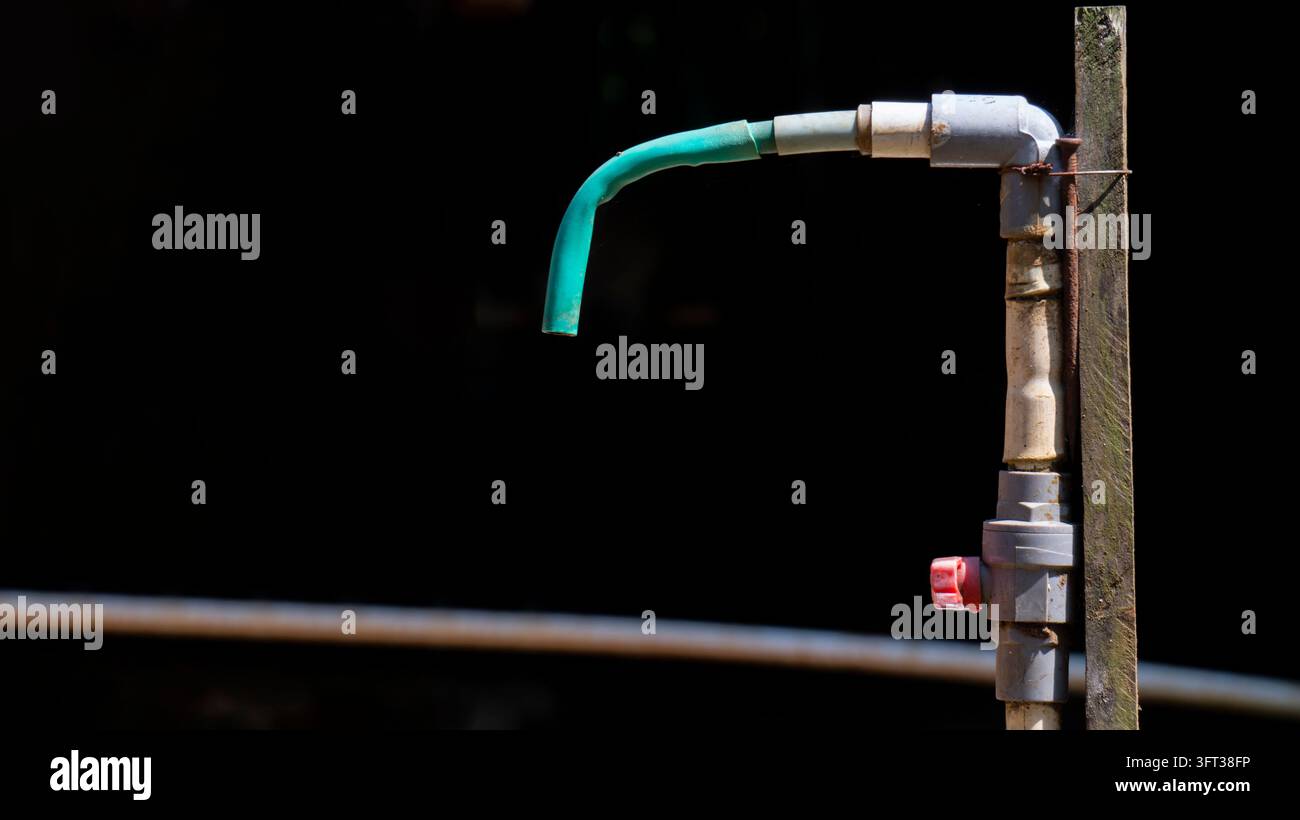 Rubinetto per esterni con tubo su sfondo scuro Foto Stock