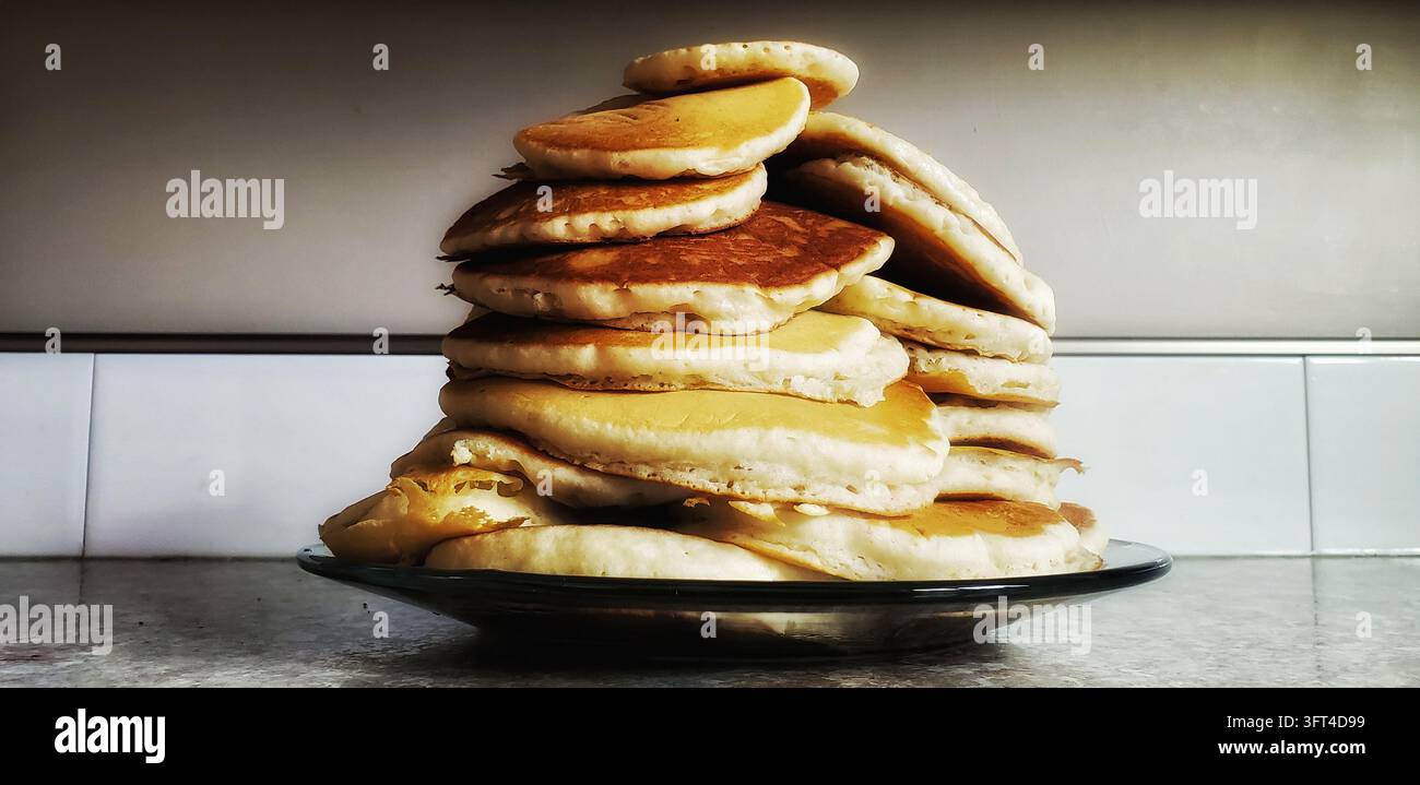 Grande pila di pancake soffici dorati ammucchiati alti su un piatto da portata Foto Stock