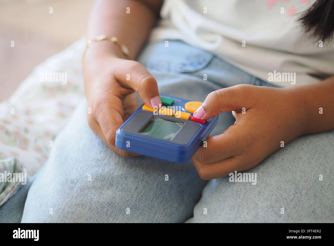 Un bambino tiene un dispositivo di gioco portatile ed è concentrato sullo schermo.. Foto Stock
