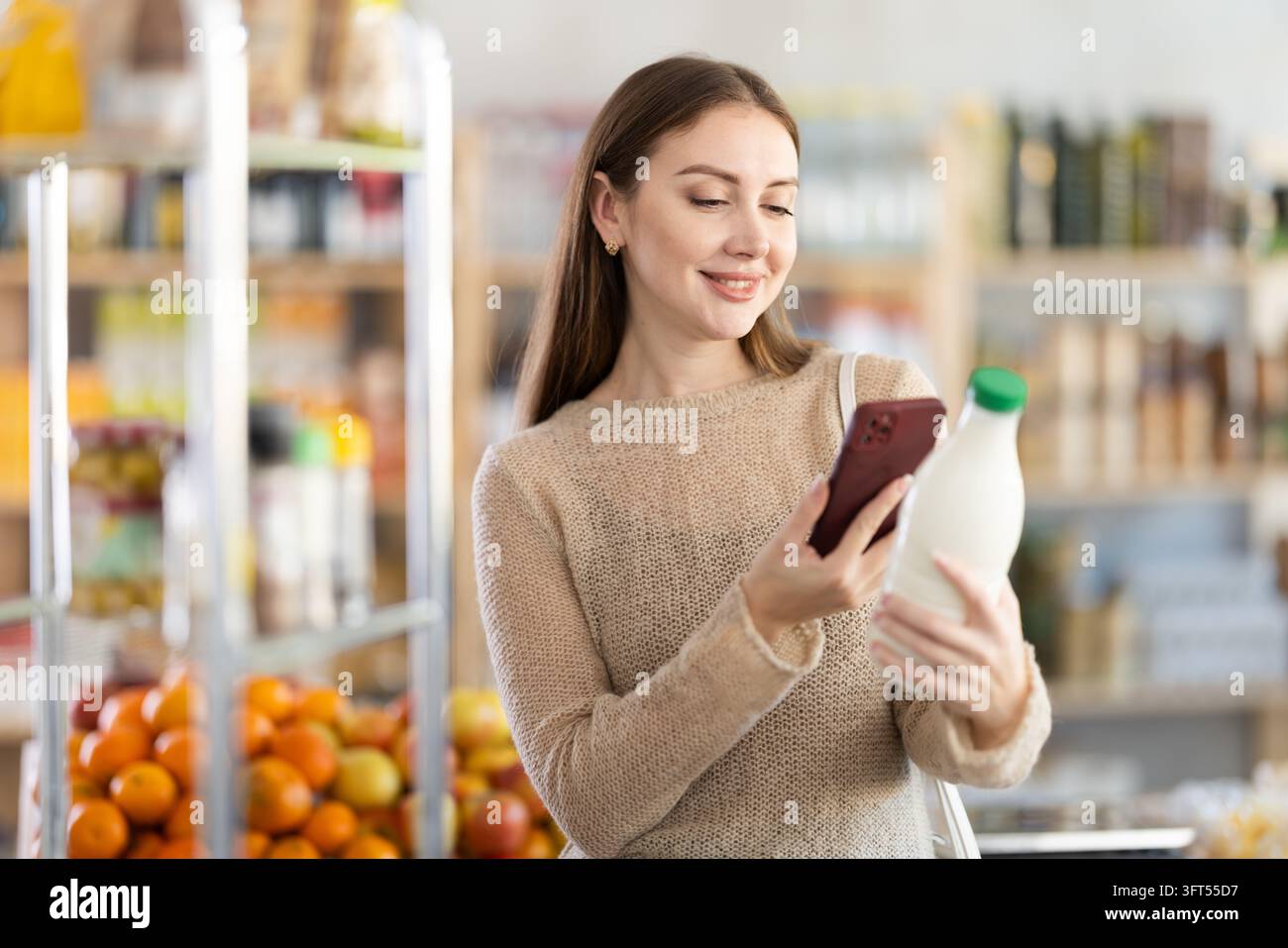 L'acquirente donna esegue la scansione del codice QR sull'etichetta del latte nel negozio di alimentari Foto Stock