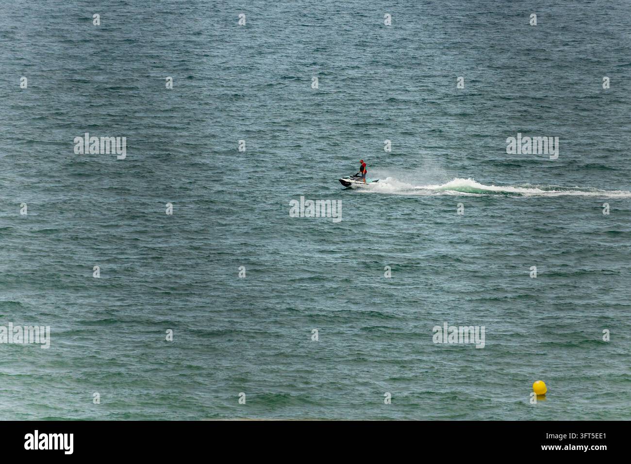 Pilota di jetski che sfreccia sull'acqua aperta Foto Stock