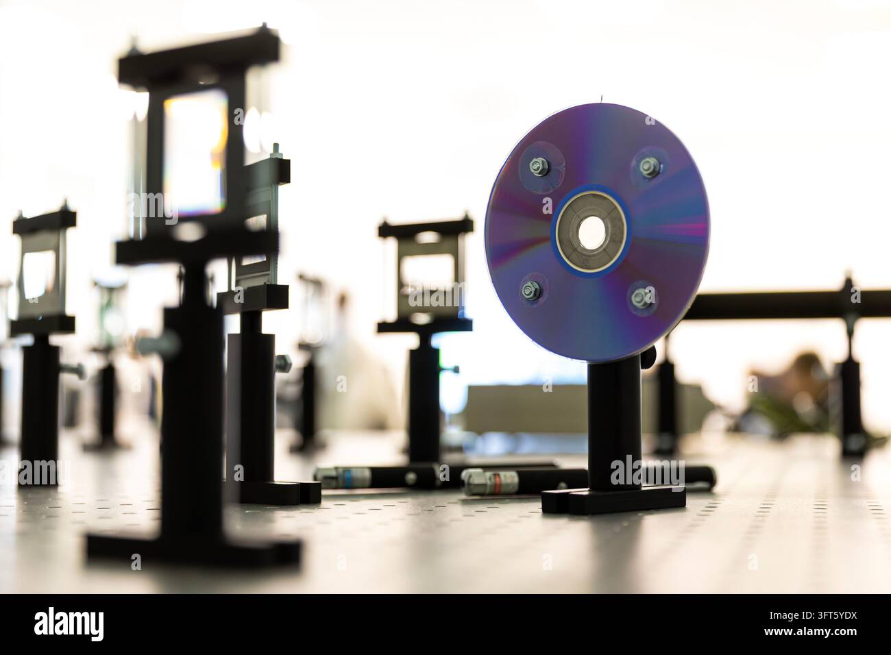 Configurazione ottica sperimentale su un breadboard ottico, con un disco ottico montato come elemento riflettente o diffrattivo su un supporto regolabile, un Foto Stock