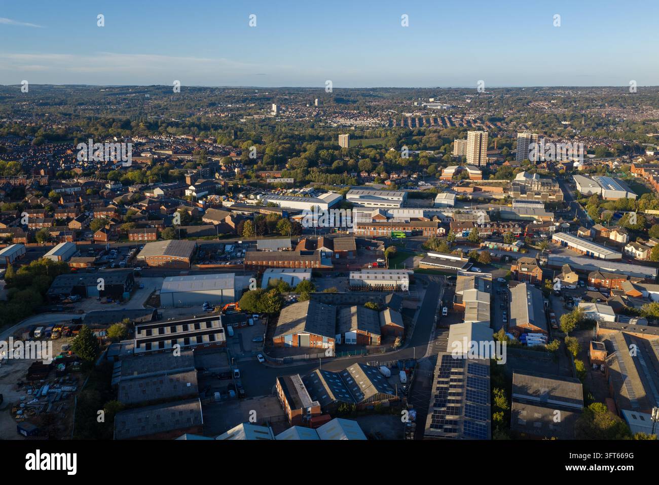 Vista aerea nel tardo pomeriggio su magazzini industriali, unità commerciali e periferie residenziali a Wortley, Leeds, che si estendono verso la collina lontana Foto Stock