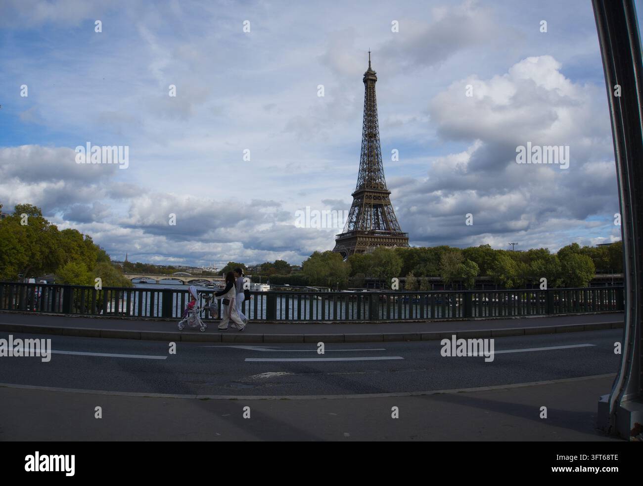 Pedoni che camminano lungo il Pont de Bir-Hakeim con la Torre Eiffel che si erge sullo sfondo sotto un cielo blu nuvoloso a Parigi, Francia. Foto Stock