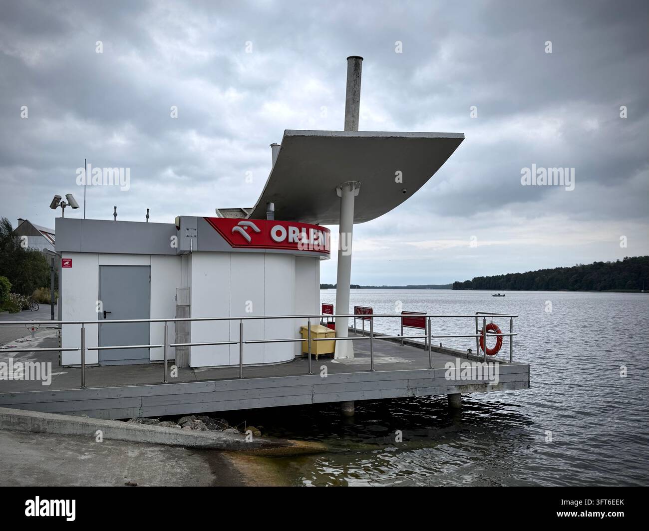Una struttura galleggiante di stazione di servizio marittima Orlen situata su un molo di legno vicino al lago, che mostra la segnaletica del marchio e un moderno tettoia architettonica - Immagine stock catturata con smartphone