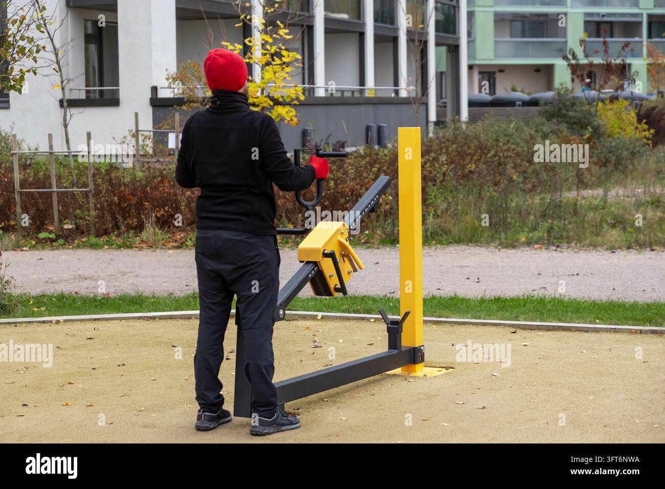 Un uomo fa esercizio su una macchina per la pressione toracica all'aperto in un luogo pubblico in Finlandia in una giornata autunnale. Uno stile di vita urbano attivo, autodisciplina, salute Foto Stock