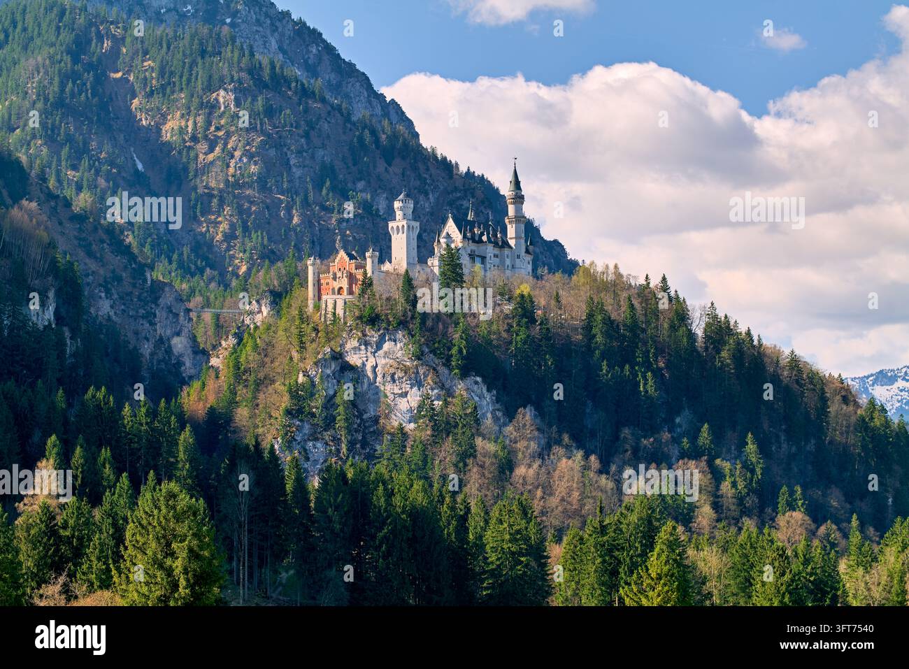 Vista primaverile del palazzo del XIX secolo del re Ludovico II su una cresta rocciosa nelle Alpi bavaresi, Germania, con il ponte Marienbrücke e le cime innevate Foto Stock