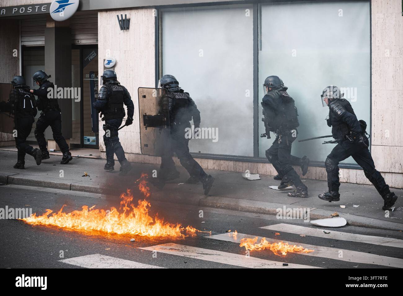 Parigi, Francia - 09 febbraio 2019: Fila di poliziotti anti-sommossa in servizio di guardia accanto a un incendio stradale. Foto Stock