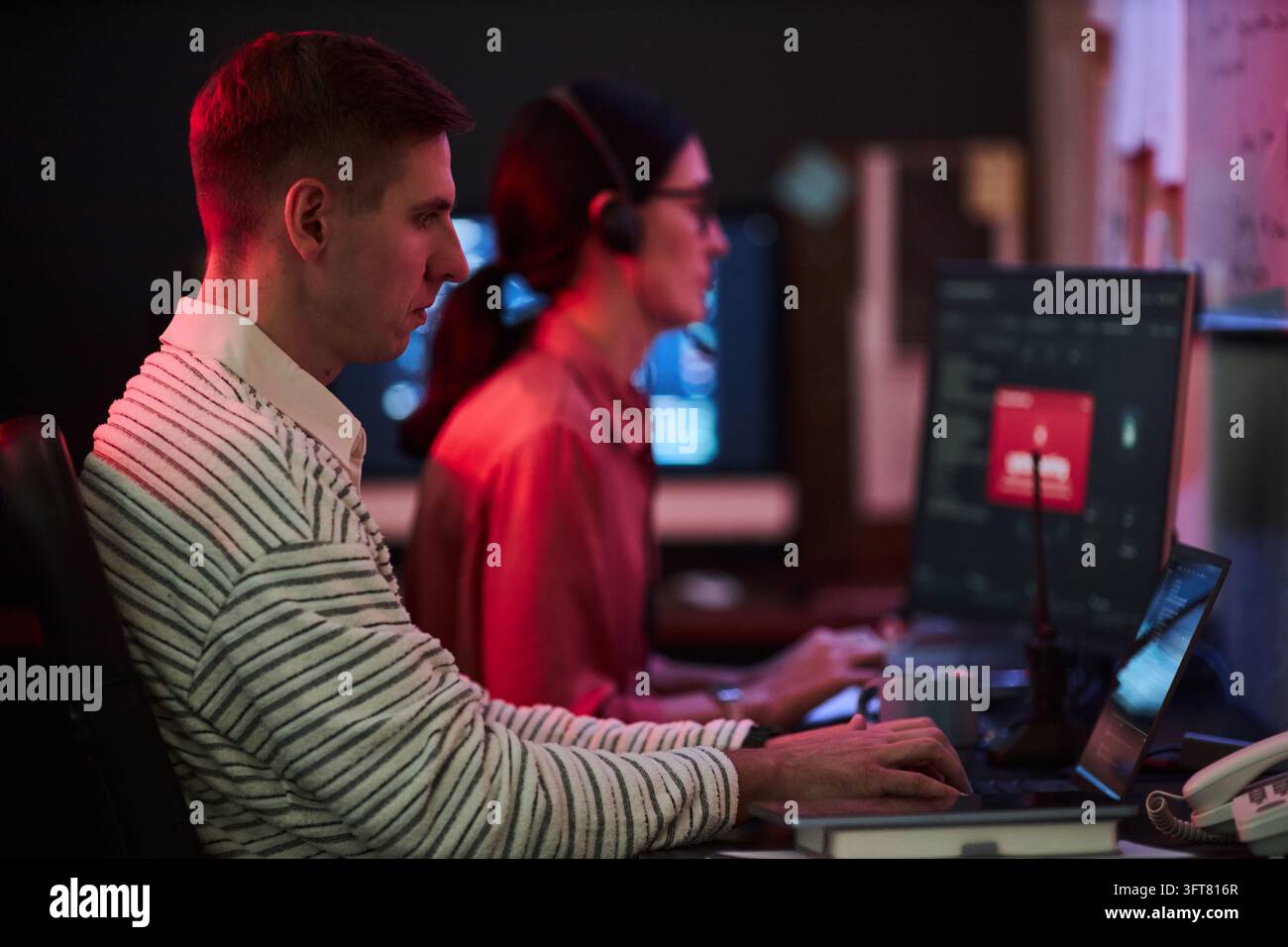 Uomo e donna che lavorano su una minaccia alla cybersecurity in un ufficio IT Foto Stock