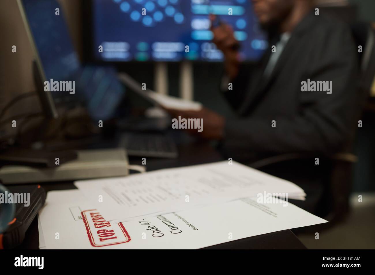 Uomo nero che legge file riservati in un ufficio di sicurezza informatica Foto Stock