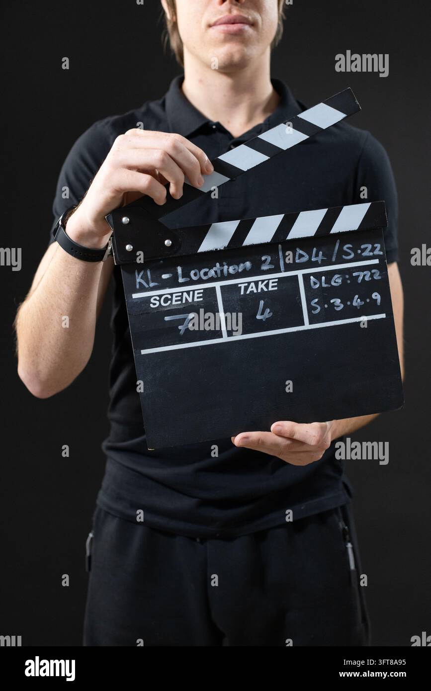 Uomo che tiene un ardesia, solleva la parte superiore incernierata, in piedi in studio, indossa una polo nera, tasche con cerniera Foto Stock