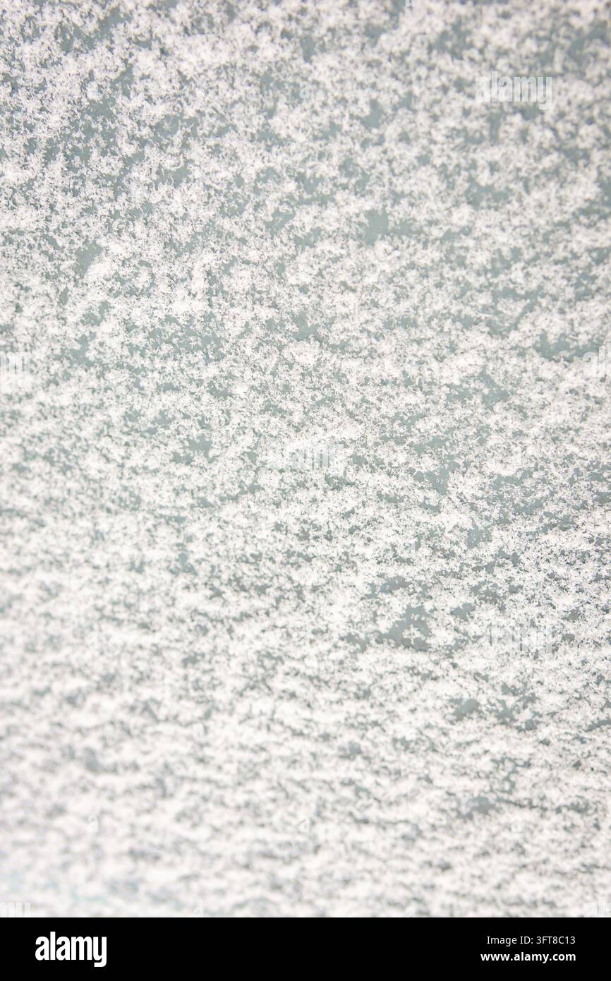 Superficie in vetro smerigliato coperta di neve bianca e sfondo a motivi di ghiaccio con spazio di copia verticale. Foto Stock