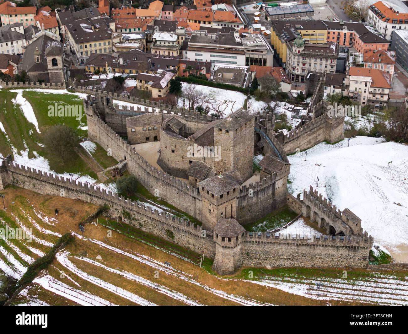 Vista aerea della storica fortezza di Castelgrande con mura in pietra, torri e cortili circondati da terreni innevati e dal paesaggio urbano Foto Stock