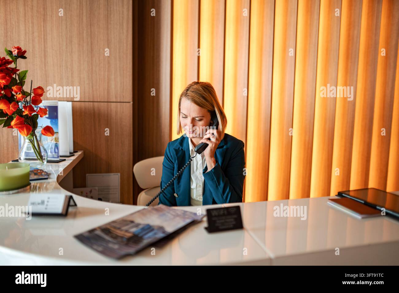 Addetta alla reception che risponde a una chiamata telefonica alla reception dell'hotel Foto Stock