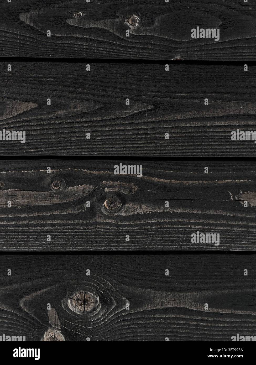 Primo piano di assi di legno tinte di nero scuro che mostrano venature visibili, nodi e una texture rustica consumata - Immagine stock catturata con smartphone
