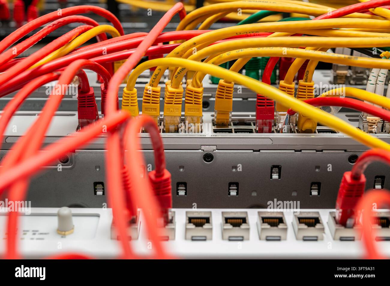 Groviglio disorganizzato di cavi di patch Ethernet instradati attraverso switch di rete e pannelli di patch all'interno di un rack di server, comunemente noto come spaghetti di cavi. Foto Stock