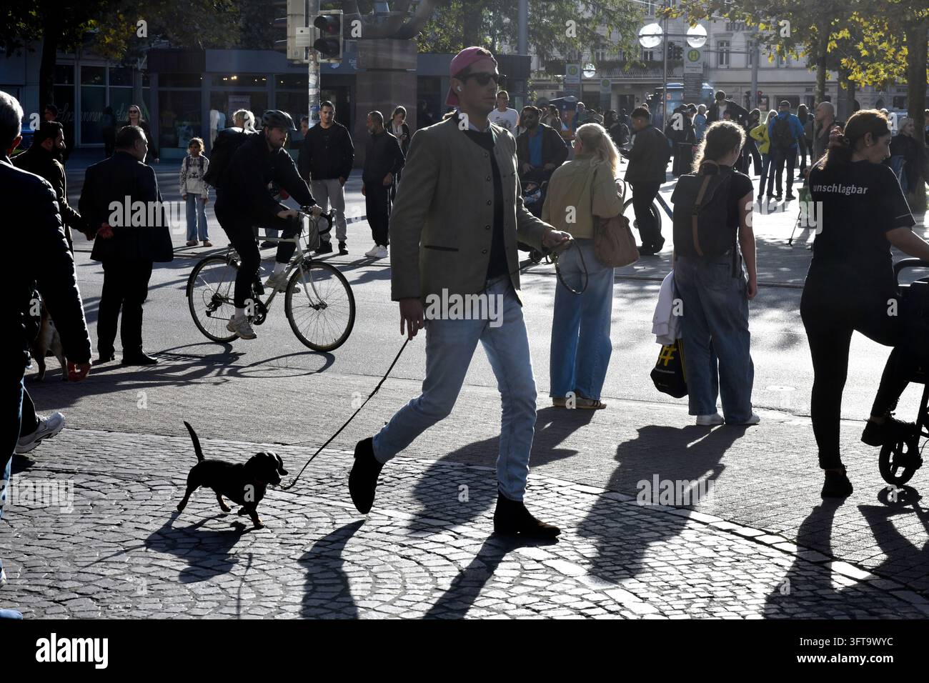 Uomo alto che passeggia un cane piccolo a Heidelberg, Germania. Foto Stock