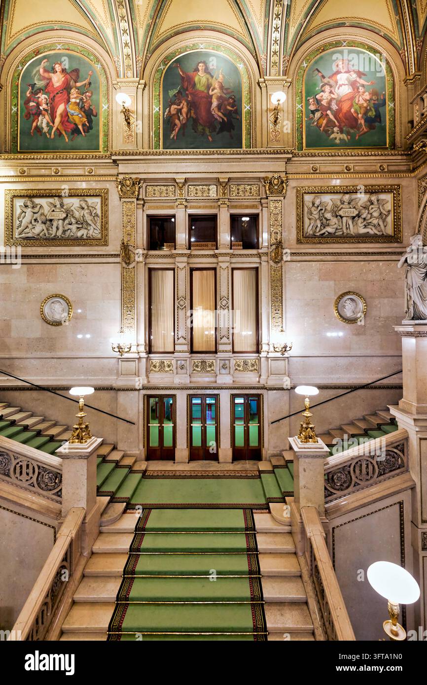 Interno della Staatsoper di Vienna sulla Ringstraße con scalini in marmo, tappeto verde, lunette dipinte e rilievi di balletto e opera Foto Stock