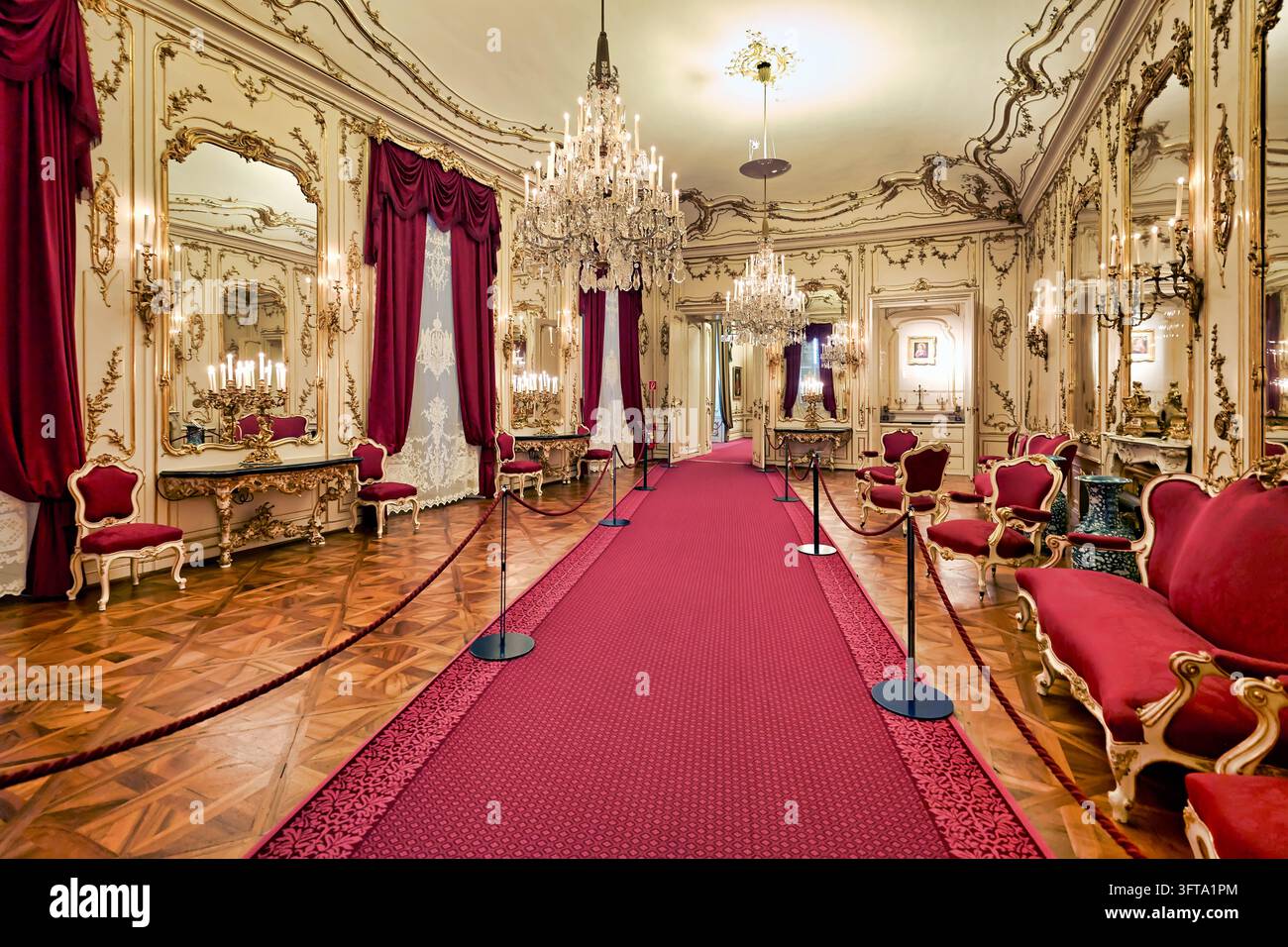 Salone bianco e dorato con lampadari di cristallo, specchi dorati e sedie di velluto rosso, recintato per i visitatori in un palazzo storico viennese. Foto Stock
