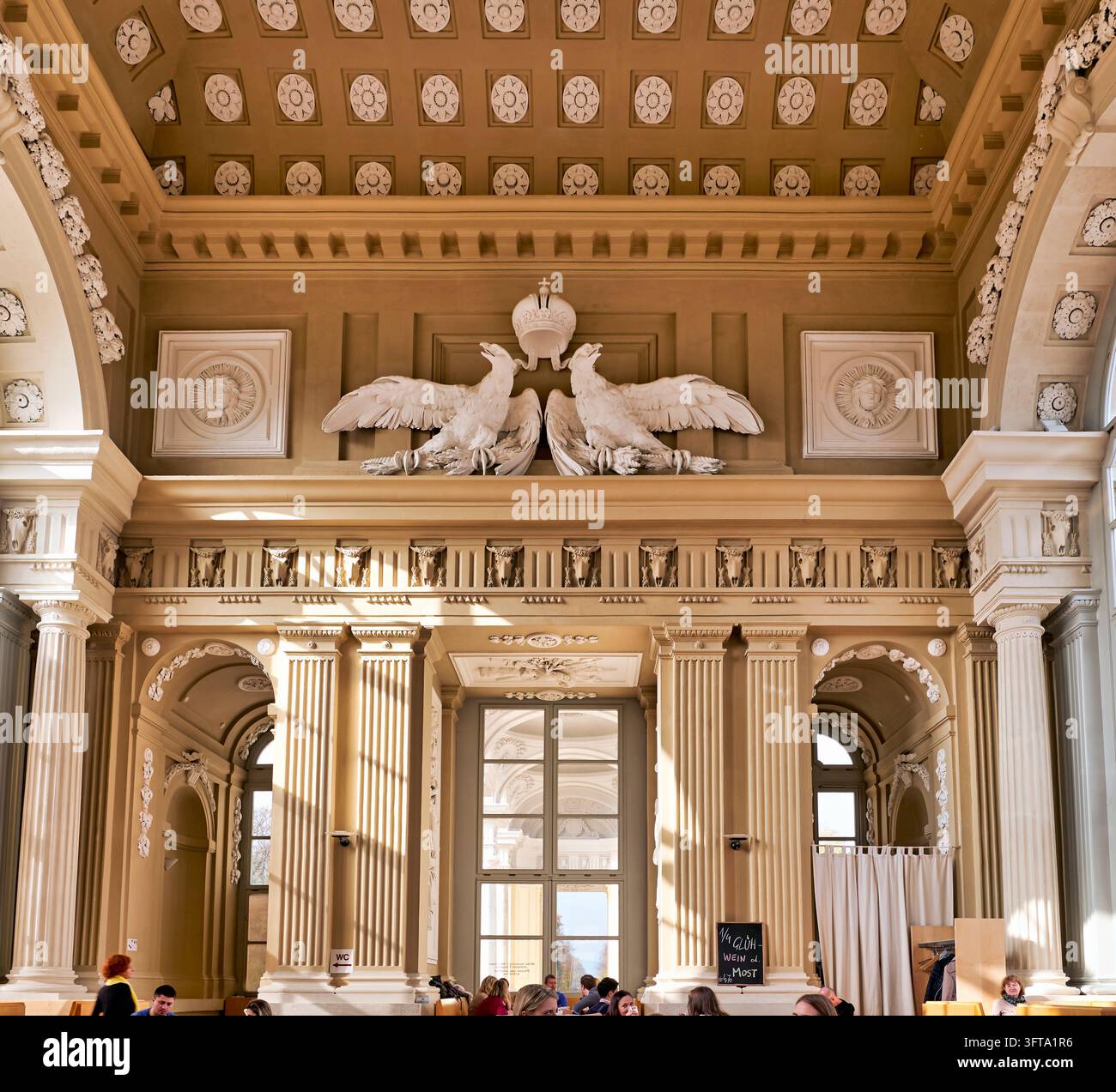 I visitatori sono seduti sotto un soffitto a cassettoni, aquile imperiali e una corona nella sala del caffè della Gloriette, Giardini di Schönbrunn, Austria Foto Stock