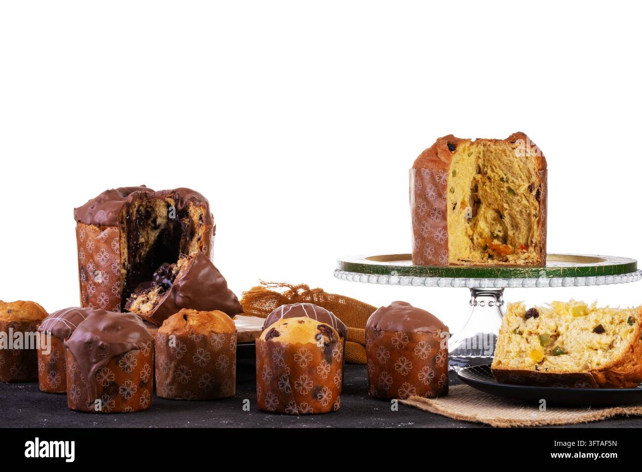 Assortimento di dolci tradizionali italiani per il Natale, tra cui panettone alla frutta e chocotone ripieno di cioccolato, disposti su una superficie scura contro Foto Stock