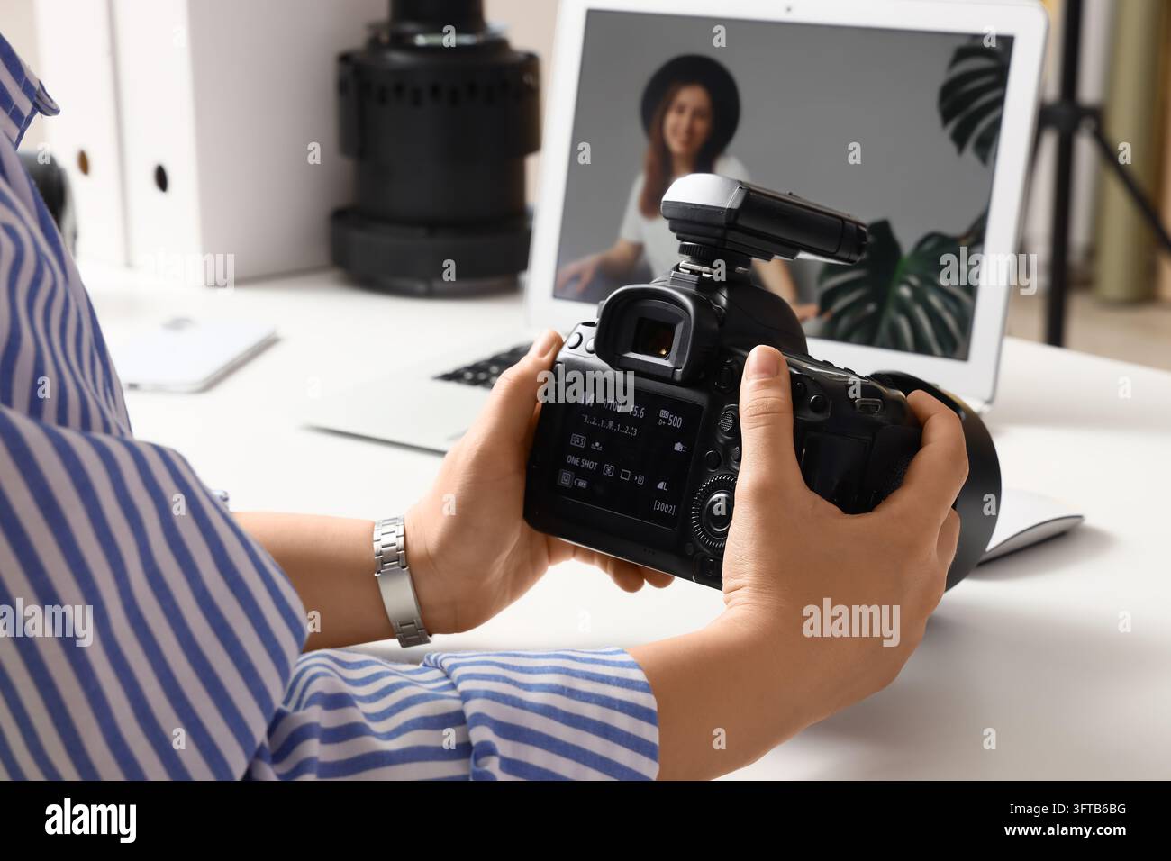 Flusso di lavoro fotografico e editing digitale, fotografo che controlla le immagini sullo schermo della fotocamera con laptop in uno spazio di lavoro creativo in studio per la post-produzione Foto Stock
