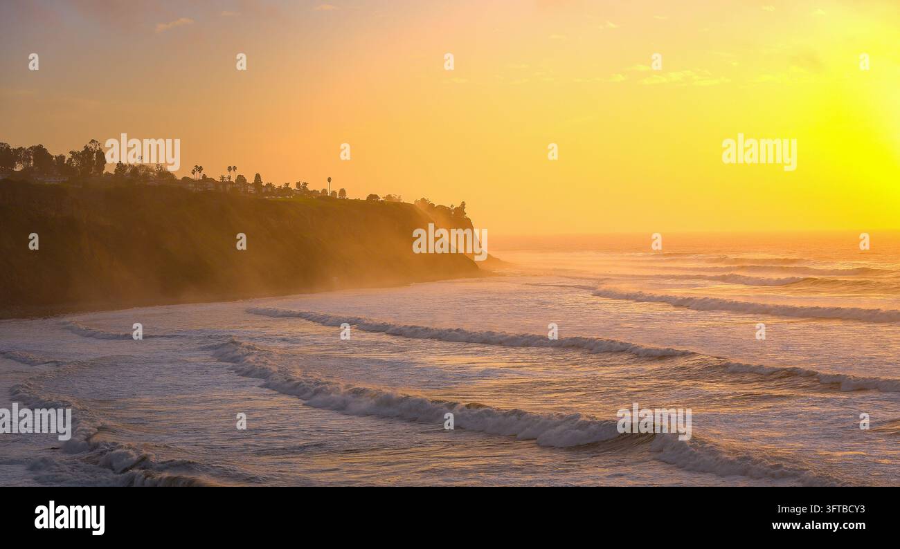 Tramonto dorato che illumina le onde dell'Oceano Pacifico lungo una costa frastagliata in California. Foto Stock