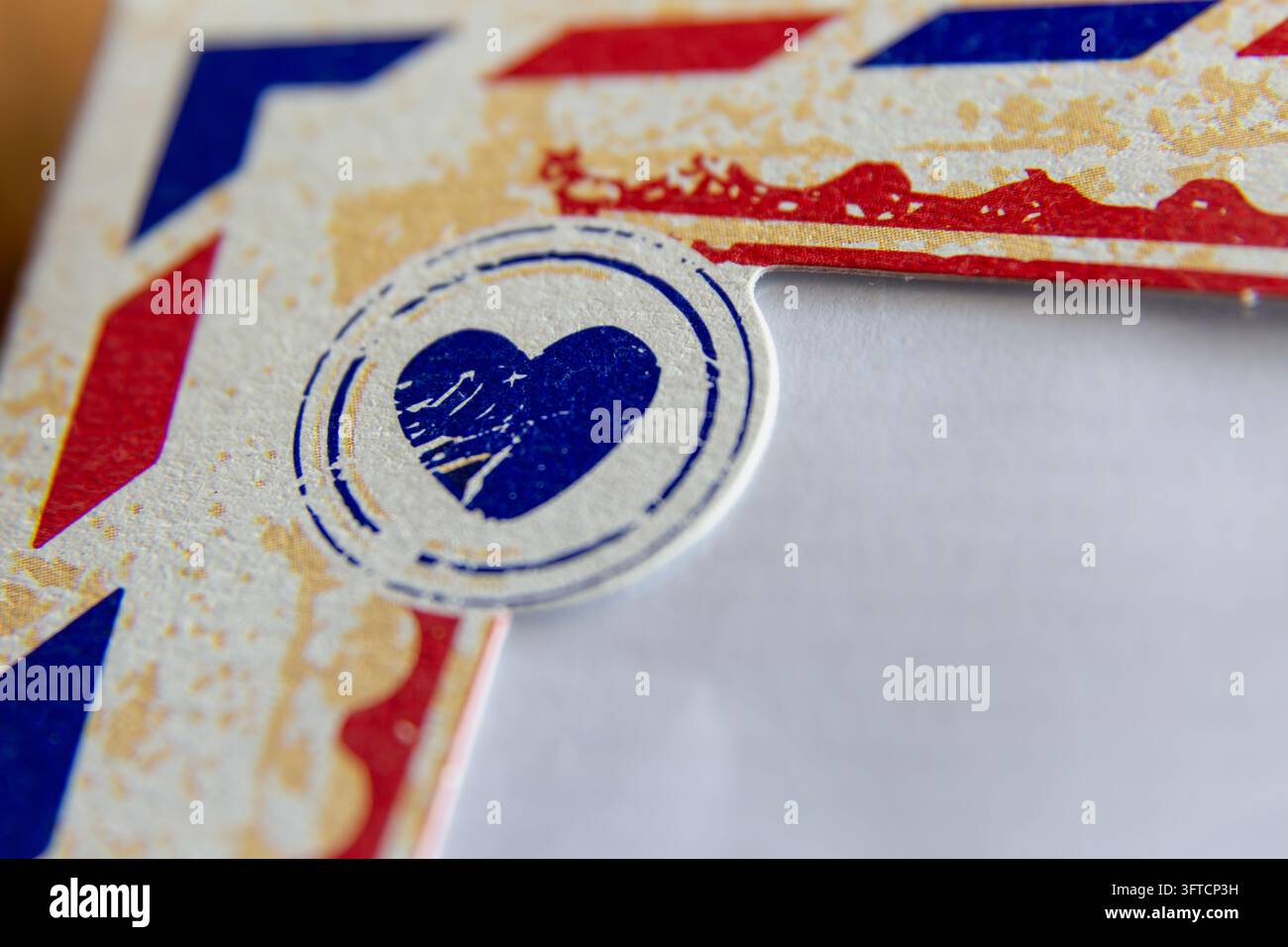 Prima vista di un timbro a forma di cuore blu circolare con una texture consumata e grunge e graffi, stampato su uno sfondo di carta invecchiata e fantasia. Foto Stock