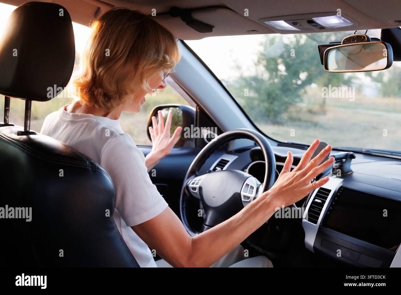 Donna frustrata che urla, alzando le mani dietro il volante. Difficoltà di guida, stress del conducente principiante, apprendimento della guida, ansia, perdita di fiducia Foto Stock