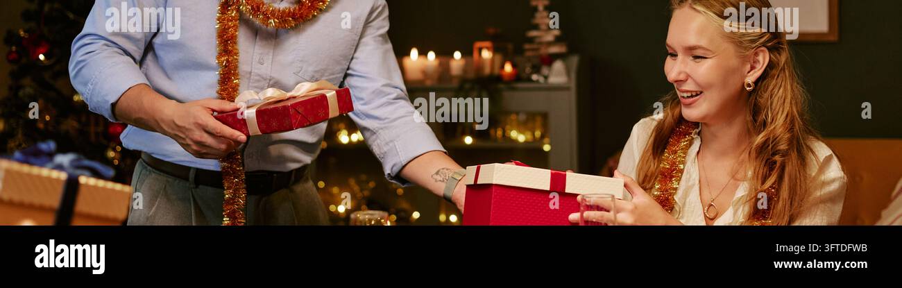 Testa di una donna che riceve un regalo di Natale dal partner durante la cena delle festività Foto Stock
