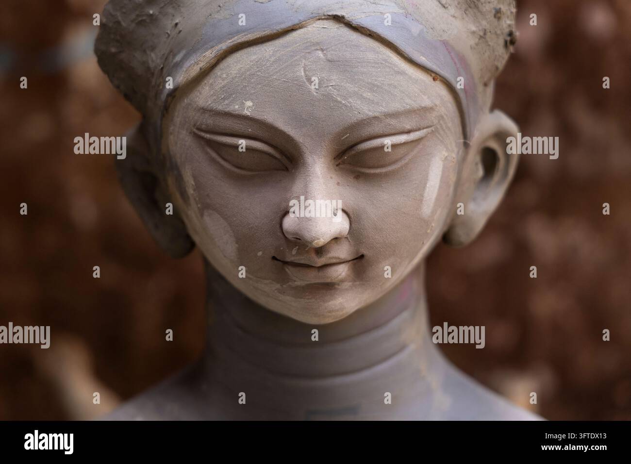 Viso in argilla grigia morbida di una figura di dea con un piercing al naso e un dolce sorriso nel distretto di Kumartuli, Bengala Occidentale, Kolkata, India Foto Stock