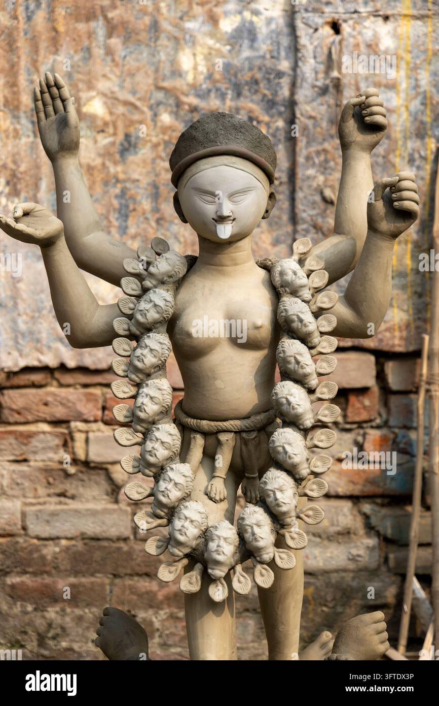 Figura di dea in argilla cruda con braccia sollevate e una collana di piccoli volti in argilla contro un vecchio muro a Kumartuli, Bengala Occidentale, Kolkata, India Foto Stock