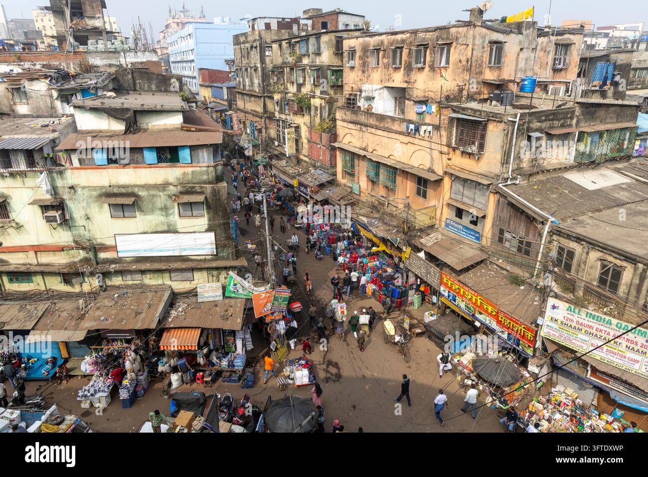 Scena elevata di una strada del bazar affollata di pedoni, bancarelle colorate e insegne di negozi tra vecchi edifici, Bengala Occidentale, Kolkata, India Foto Stock
