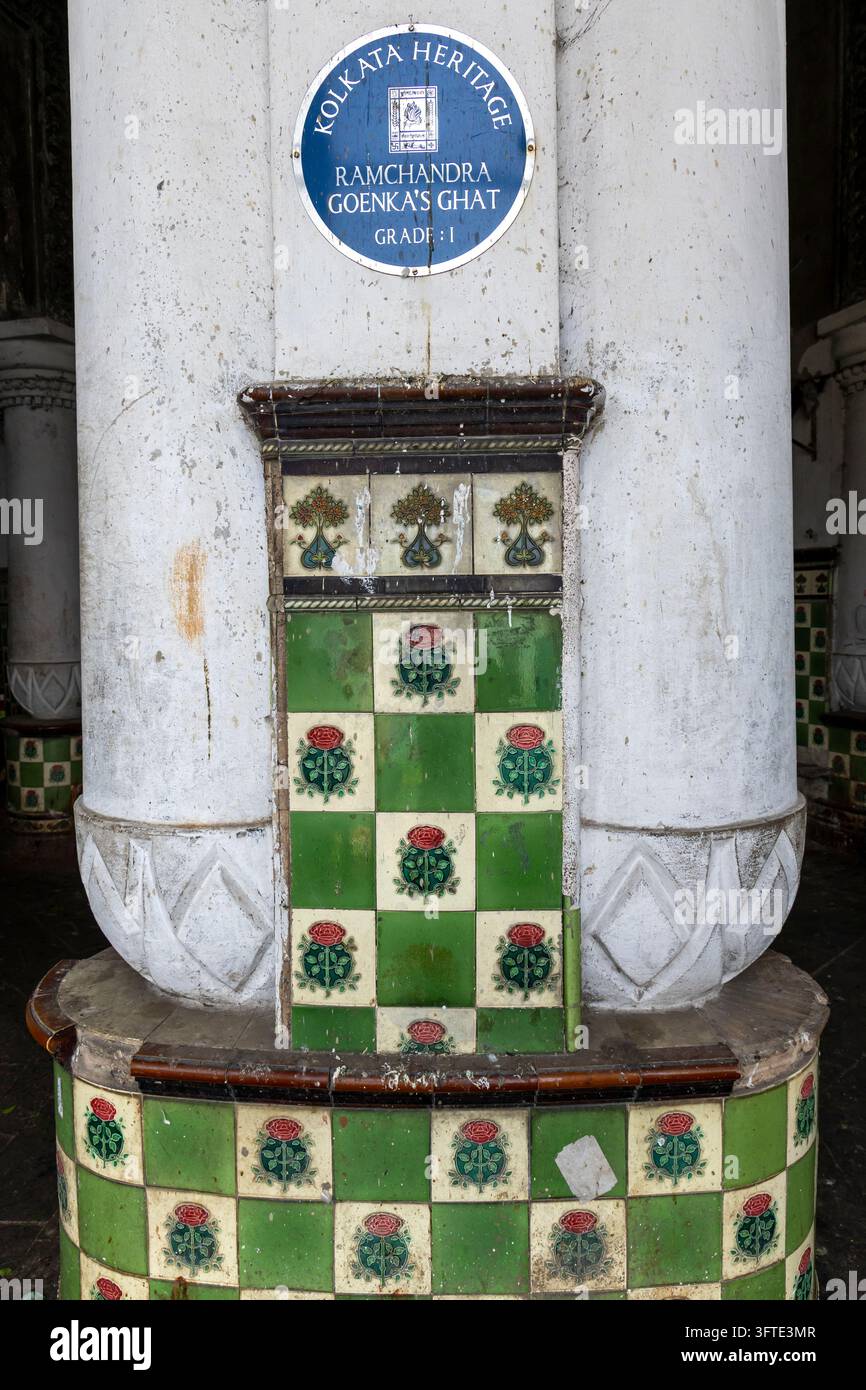 Una targa ereditaria blu e rotonda è montata su un pilastro bianco sopra piastrelle a motivi di rose al mercato dei fiori, Bengala Occidentale, Kolkata, India Foto Stock