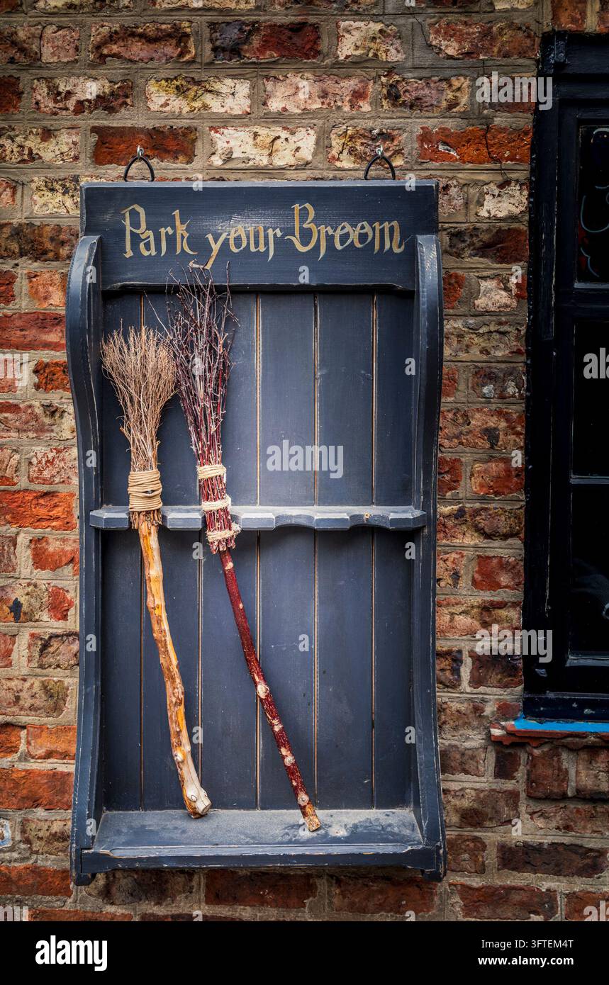 Due scope di strega su un portasciugamani Park your Broom contro un muro di mattoni a York Foto Stock